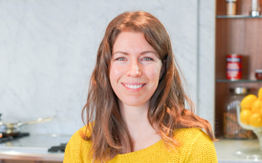 Portrait of founder Ashlee Steinhauer smiling in her kitchen.